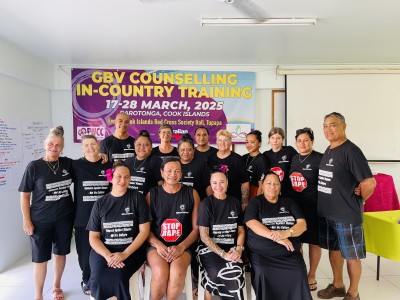 A group of people both seated and standing smile for the camera in front of a banner.