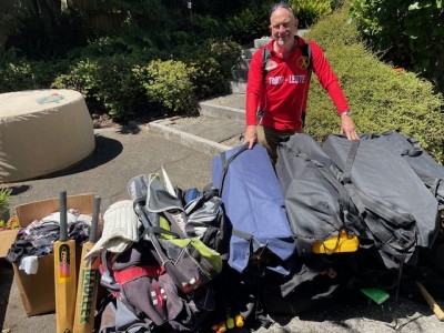 Mark stands over a pile of cricket gear that has been donated