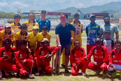 A cricket team poses for a photo on the cricket field